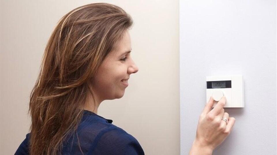 Vrouw draait thermostaat om.